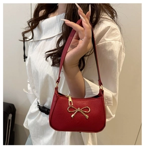 Gros plan sur un sac en cuir rouge avec détail de nœud papillon en métal doré élégant