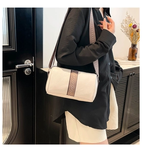 Detail of off-white cylinder bag featuring a retro geometric woven jacquard strap