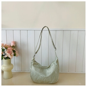 Detail of light green dumpling bag showing pleated texture and adjustable silver buckle