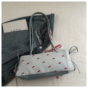 Détail du sac sous le bras bleu avec motif nœud blanc, dentelle et ruban à carreaux rouges
