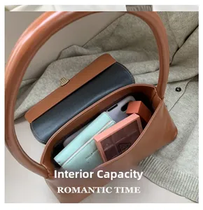 Détail intérieur du sac en cuir marron contenant téléphone et cosmétiques