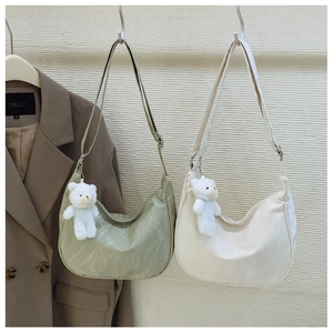 Detail of glossy pleated crescent bags in light green and cream with cute bear charms