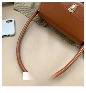 Détail du sac à main en cuir marron avec boucle dorée carrée et poignée ronde