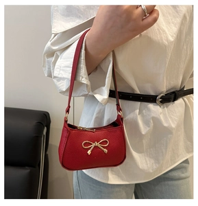 Détail du mini sac à main rouge en cuir grainé avec boucle nœud doré porté