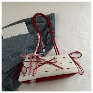 Détail d'un sac en cuir rouge avec motif à nœuds bordure dentelle et ruban à carreaux