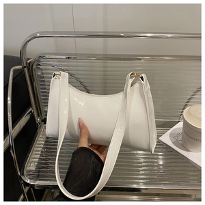 Glossy white patent leather baguette bag shown in a modern urban lifestyle setting