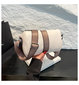 Close-up of white lychee grain leather bucket bag with wide geometric fabric shoulder strap