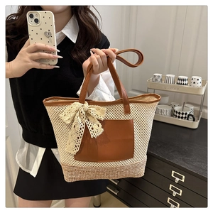 Detail of hand-woven straw tote bag featuring brown leather pocket and a lace bow detail