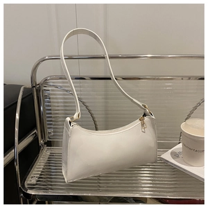Close-up of white patent leather bag with golden metal zipper on modern transparent chair
