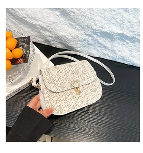 Detail of hand-woven crossbody bag with light green floral motifs and golden horseshoe clasp