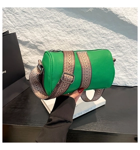 Detail of green cylinder shoulder bag with textured leather and woven strap
