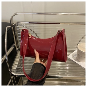 Detail of glossy deep red patent leather baguette bag with high shine finish and gold zipper