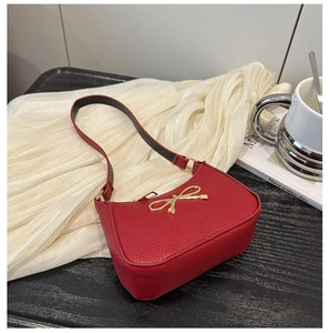 Détail d'un sac sous le bras en cuir rouge grainé avec ornement nœud doré chic