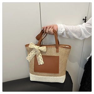 Détail d'un sac cabas en paille avec poche en cuir marron et nœud en dentelle blanche
