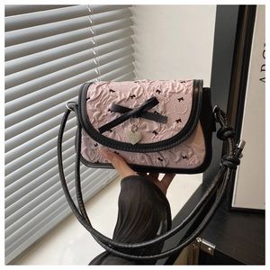 Détail du tissu plissé rose à motifs papillons et breloque coeur sur un sac à épaule
