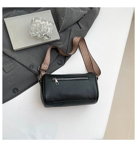 Detail of black cylindrical crossbody bag with lychee grain leather and woven strap