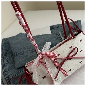 Détail du sac crème avec imprimé nœuds rouges et ruban de dentelle délicat sur l'anse