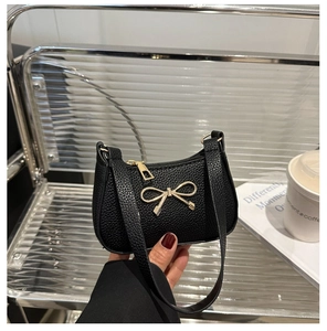 Gros plan sur la texture grainée noire avec un nœud doré métallique sur le sac à main