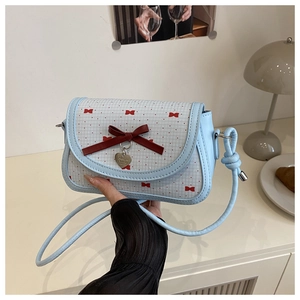 Détail du sac à main bleu clair avec motifs de papillons rouges et pendentif cœur