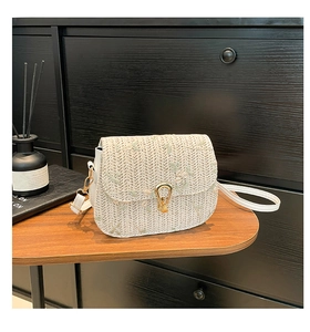 Détail de broderie florale sur sac bandoulière en paille crème avec fermoir en métal doré