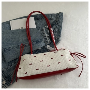 Dettaglio della borsa a spalla rossa e crema con fiocchi e nastro decorativo chic