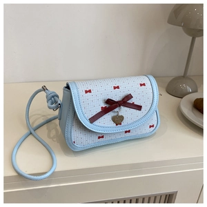 Détail du sac à main bleu clair avec nœud rouge et pendentif en forme de cœur en métal