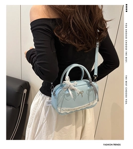 Detail of light blue bow handbag with white lace trim and checkered ribbon handle