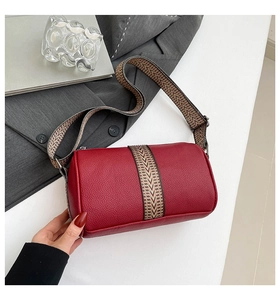 Close-up of red pebbled leather barrel bag with geometric patterned woven strap detail