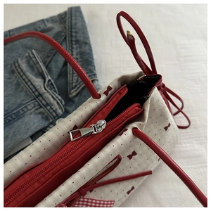 Détail de la fermeture éclair rouge et des anses sur le sac fourre-tout en toile crème