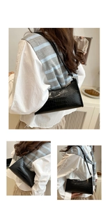 Detail of black crocodile pattern baguette bag with gold zipper and slim strap