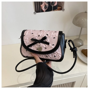 Détail du sac à bandoulière matelassé rose avec broderie papillon et pendentif en cœur