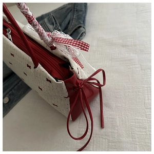 Détail du nœud rouge sur toile blanche avec dentelle délicate et ruban sur le sac à main