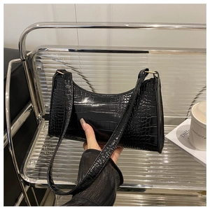 Detail of black faux crocodile leather underarm bag with gold metal link hardware