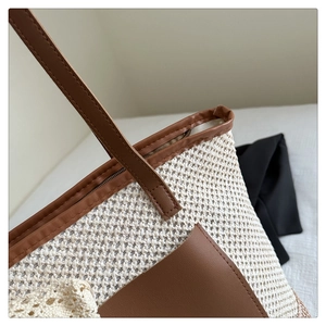 Close-up of straw tote bag with brown leather trim, zipper closure and lace details