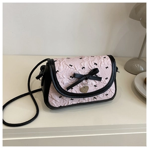 Détail du tissu jacquard rose avec nœuds noirs et pendentif cœur sur le sac bandoulière