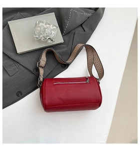 Macro detail of red pebbled leather cylinder bag with stylish geometric patterned strap