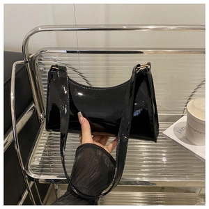 Close-up of black patent leather underarm bag with glossy finish and gold buckle hardware