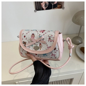 Détail d'un sac bandoulière blanc imprimé avec bordure rose et pendentif en forme de cœur
