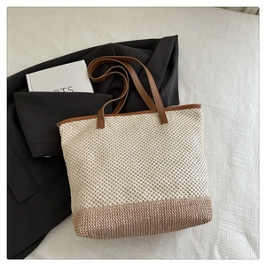 Close-up of woven straw tote bag texture with brown leather straps for summer style