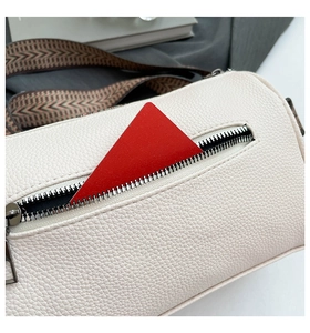 Close-up of cream lychee leather texture with metal zipper and geometric woven strap