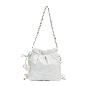 White quilted bucket bag with gold chain strap and green tulip pendant on white background