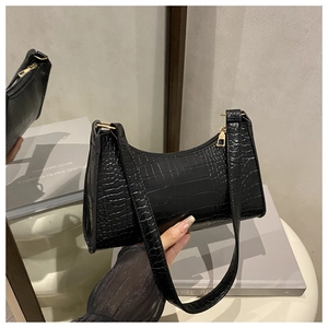 Detail of black crocodile texture handbag with golden hardware and zipper closure
