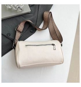 Macro detail of creamy white barrel bag with lychee texture and geometric strap
