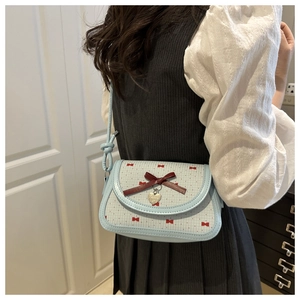 Détail d'un sac à bandoulière bleu avec motif papillon rouge et pendentif en cœur doré