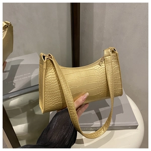 Detailed close-up of metallic gold crocodile texture on an elegant crescent shoulder bag