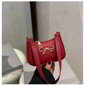 Détail du sac rouge à texture litchi avec fermoir noeud doré et anse d'épaule