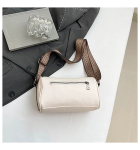 Detail of cream barrel bag with pebble leather texture and patterned webbing strap
