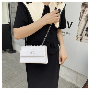 Detailed shot of a white faux crocodile texture handbag with a silver chain strap and lock