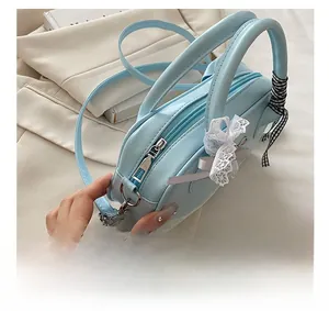 Detail view of smooth metal zipper and decorative lace bow on light blue handbag