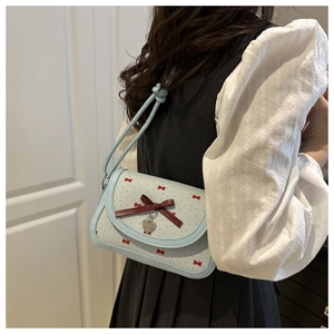 Sac bandoulière bleu clair avec imprimés nœuds rouges et détail de pendentif cœur